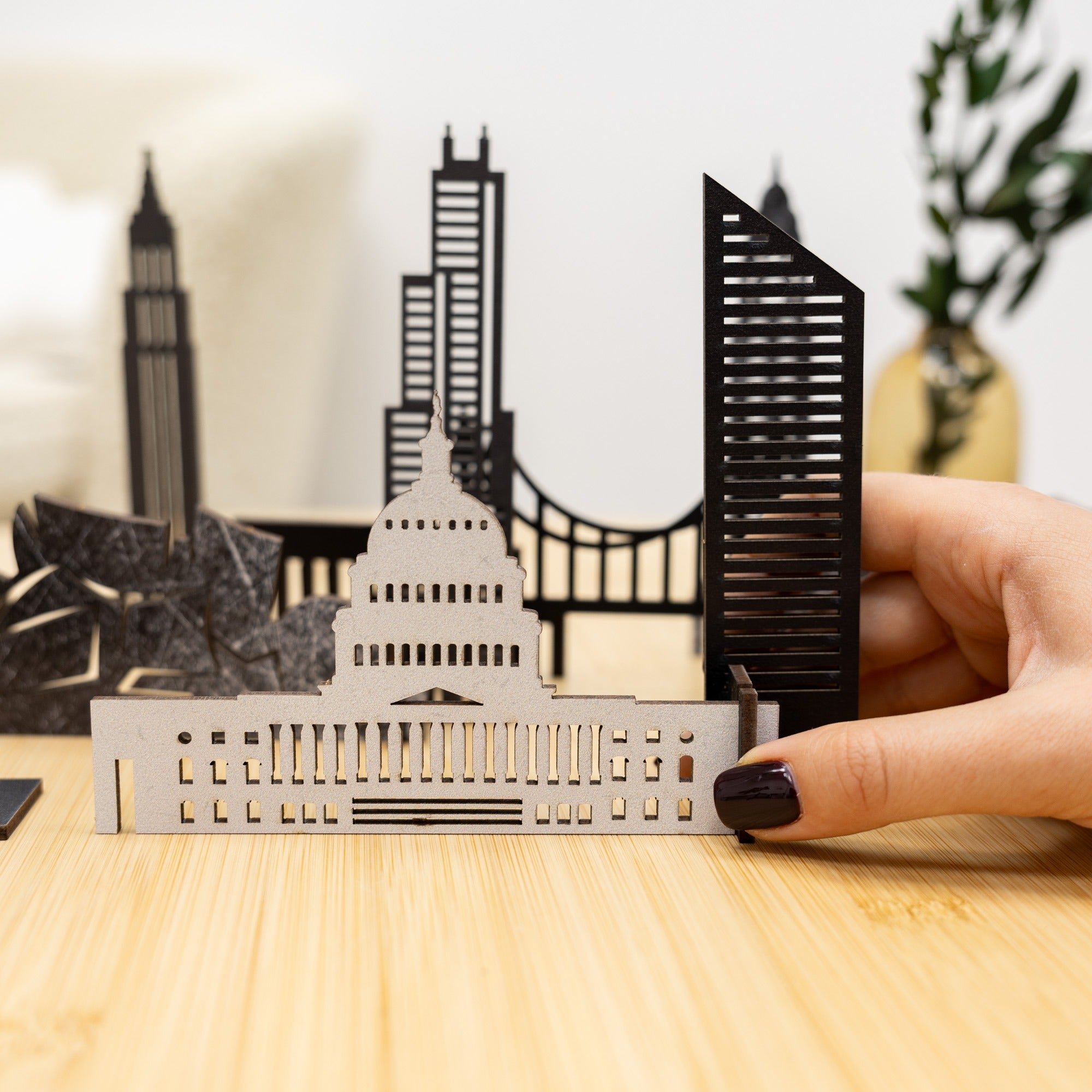 Hand holding a metallic model of a city skyline on a wooden surface