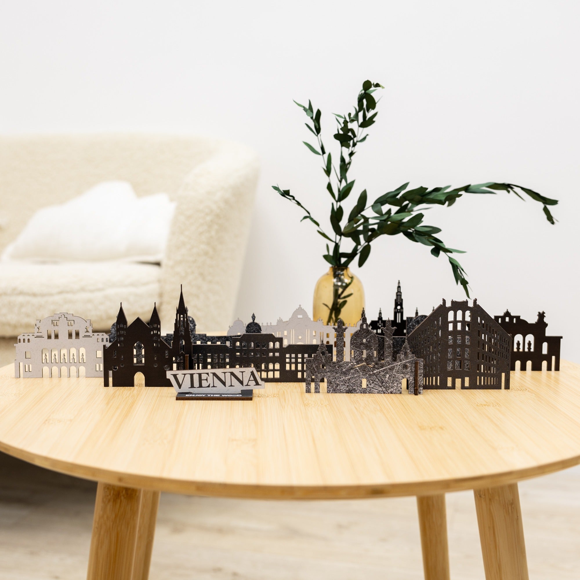 Decorative cutout of Vienna city skyline on a wooden table with a plant in the background.
