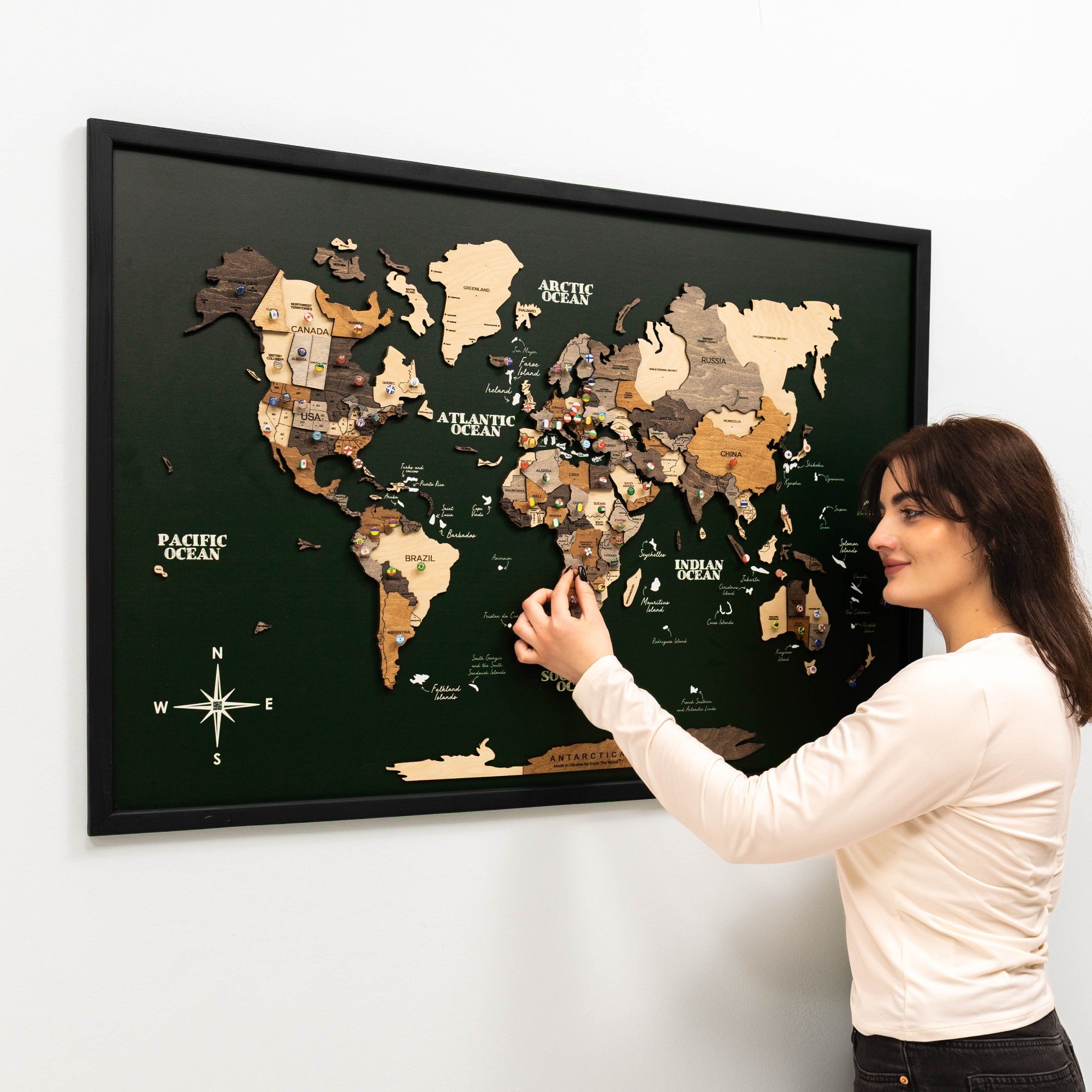 Woman pointing at a framed world map on a wall