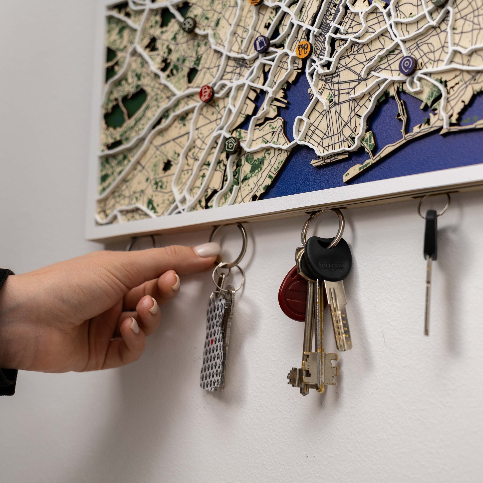 Key holder with keys attached, featuring a detailed map design on a white wall.
