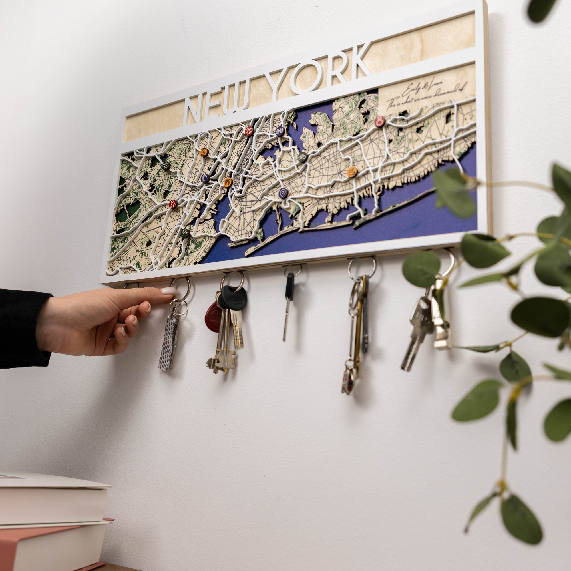 Key holder with keys attached to a wall, featuring a map of New York.