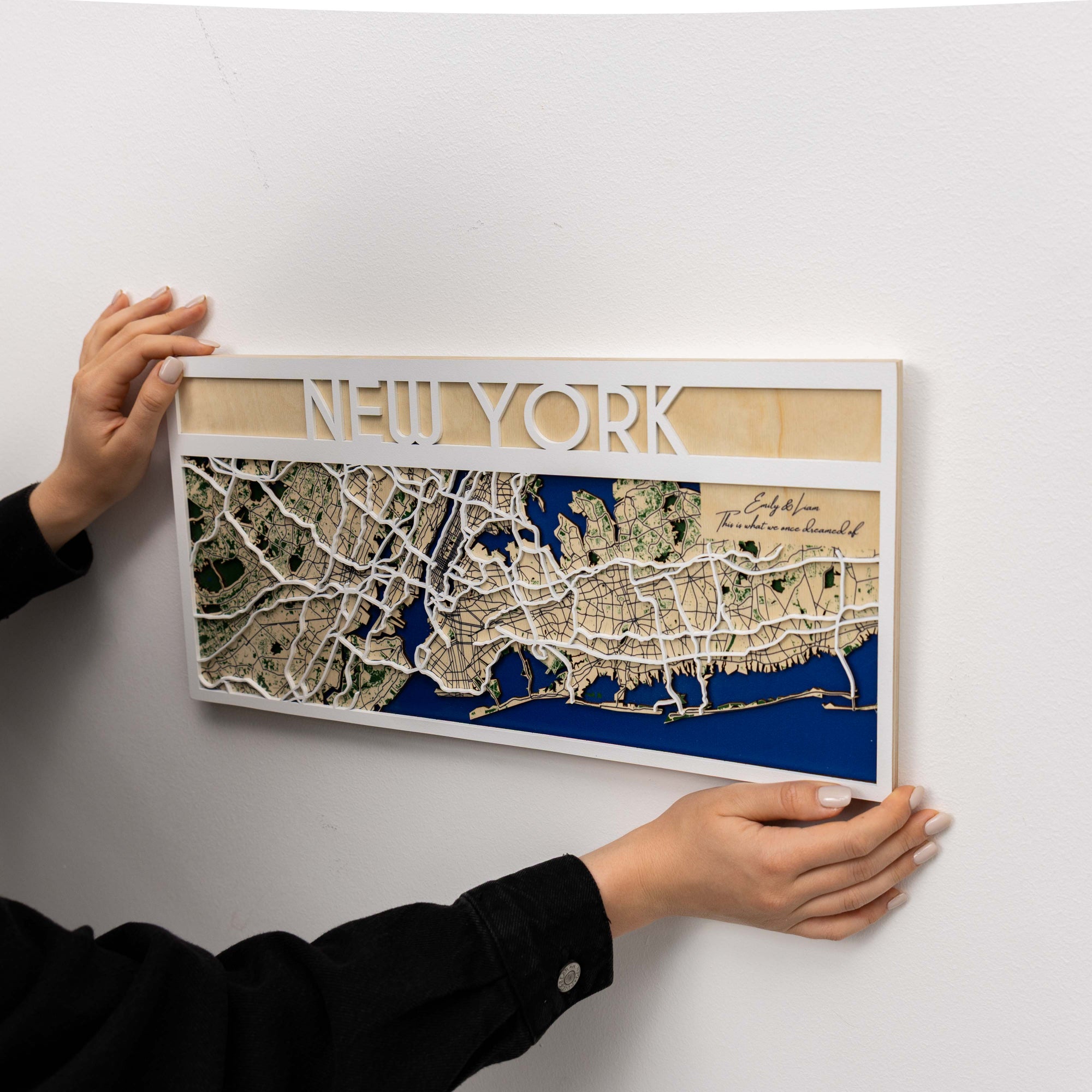 Wooden New York map with hands holding it against a white background