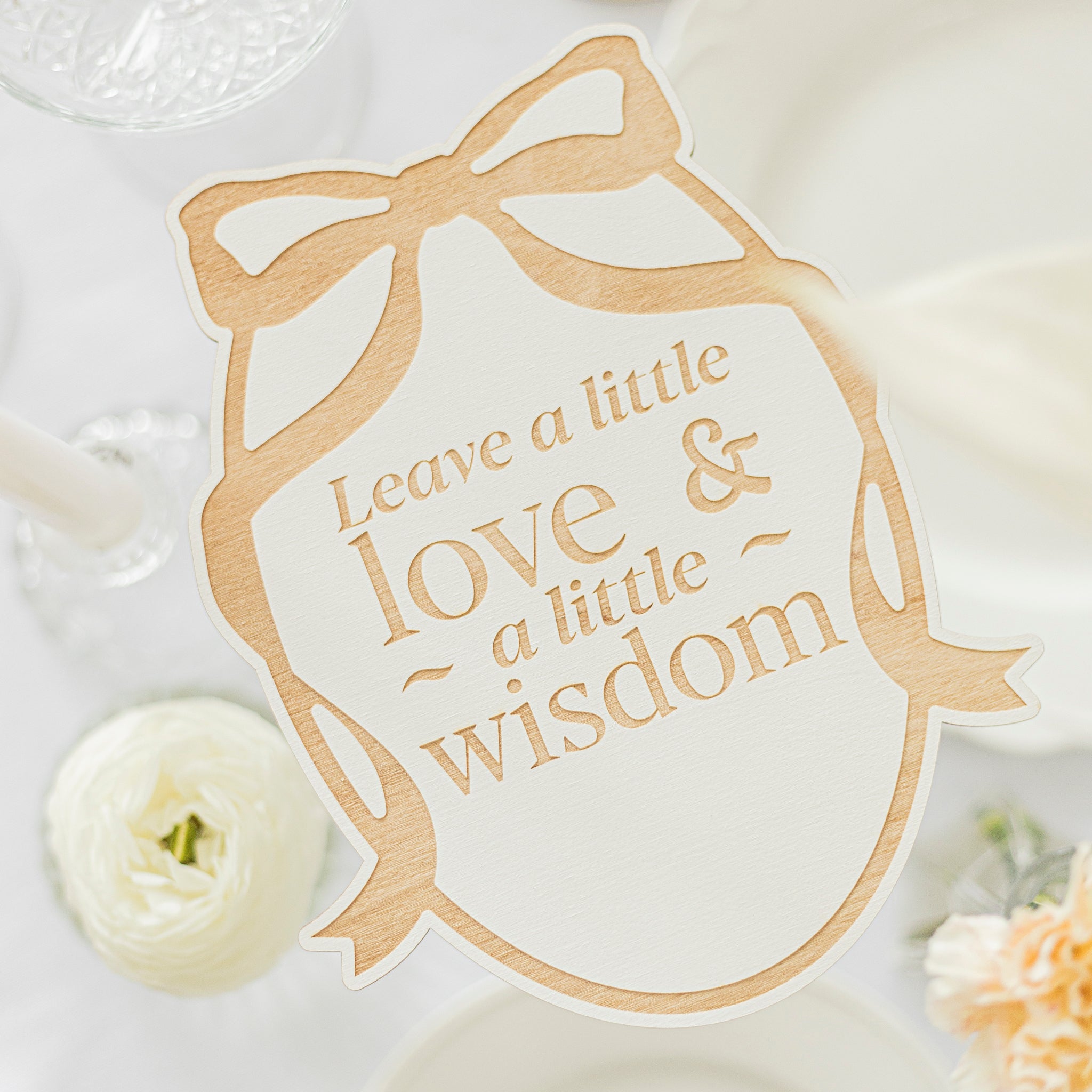 Decorative card with 'Leave a little love & a little wisdom' text on a white background with flowers.