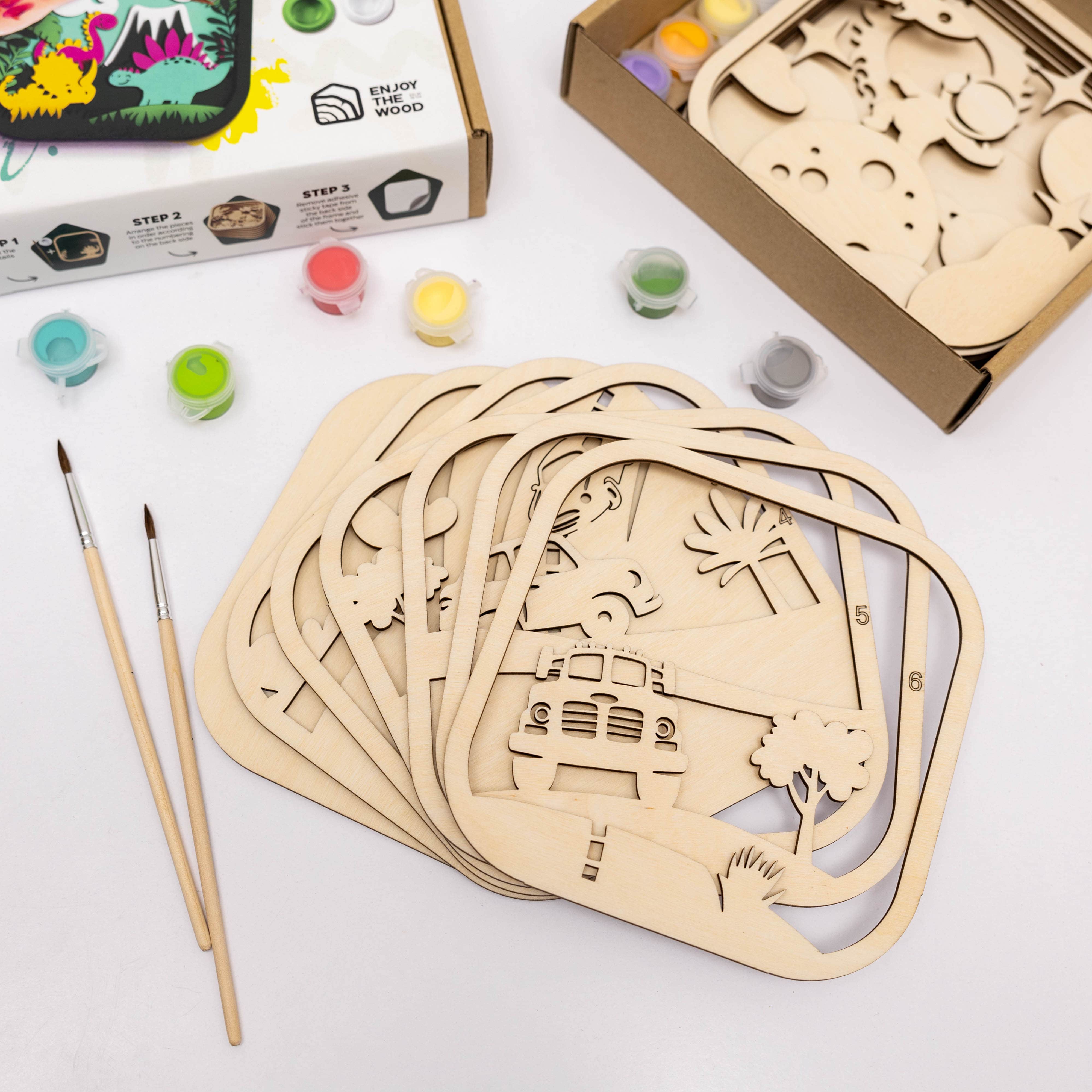 Wooden craft kits with paint and brushes on a white surface