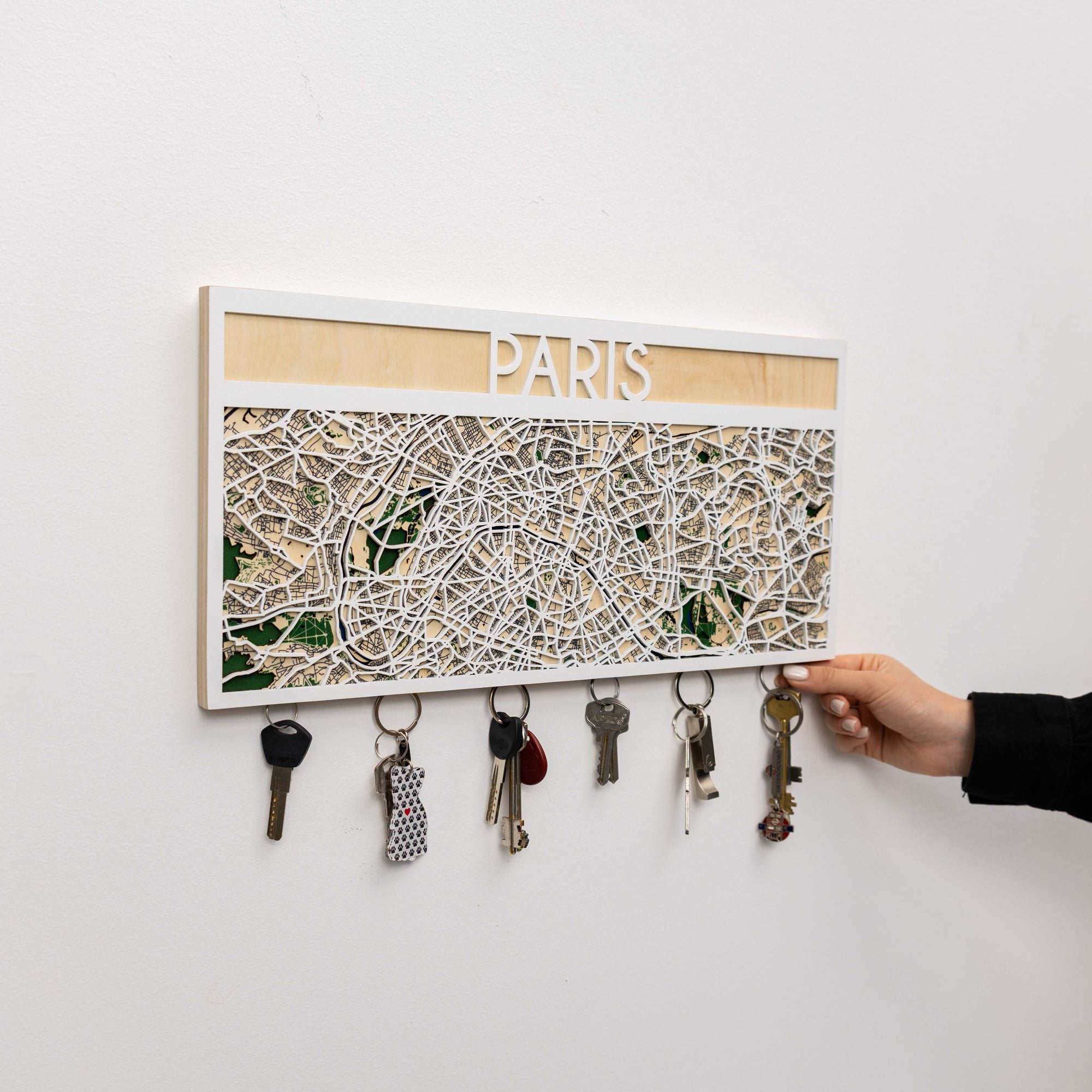 Key holder with a map of Paris and keys attached, on a white wall.