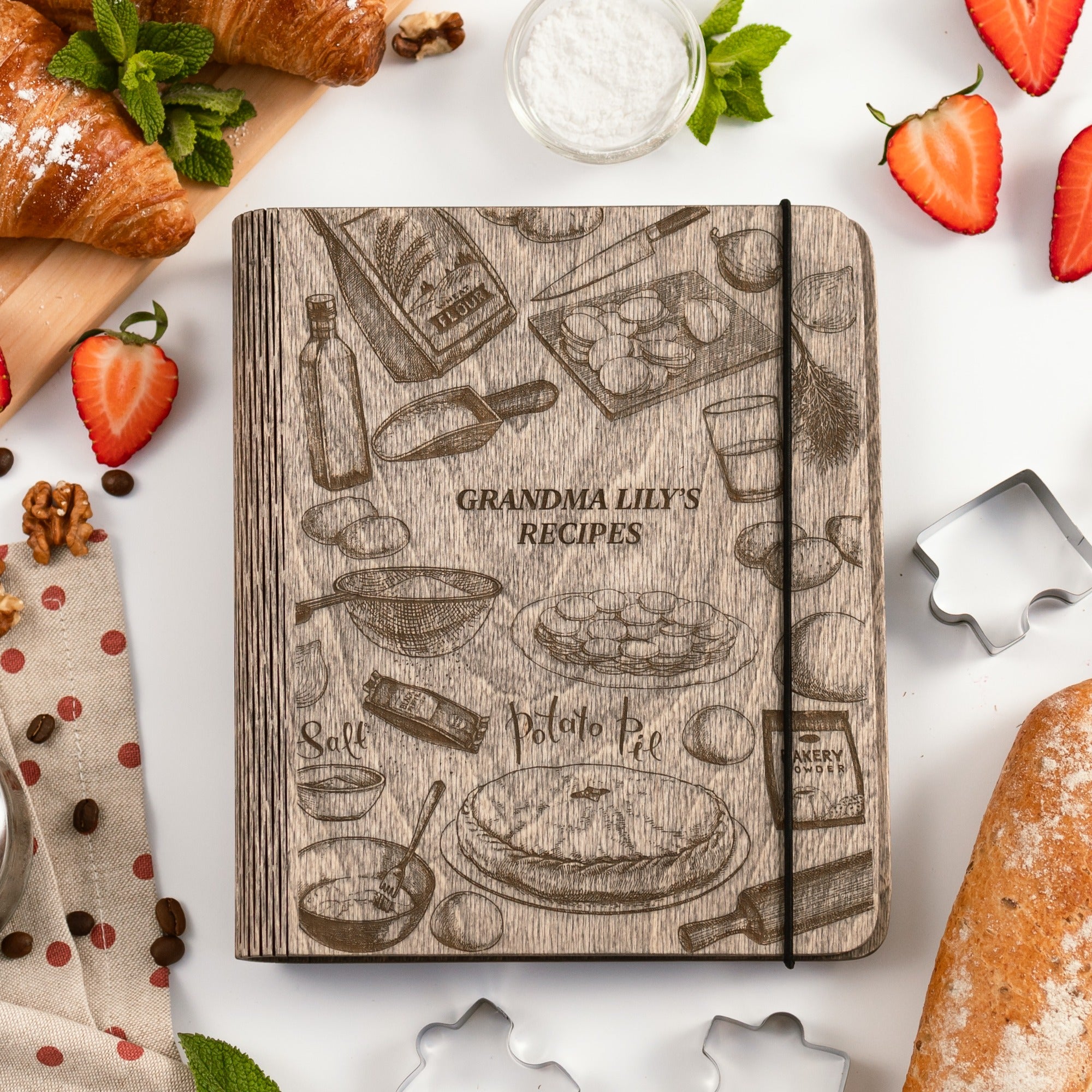 Notebook with 'Grandma Lily's Recipes' design surrounded by food items on a white surface