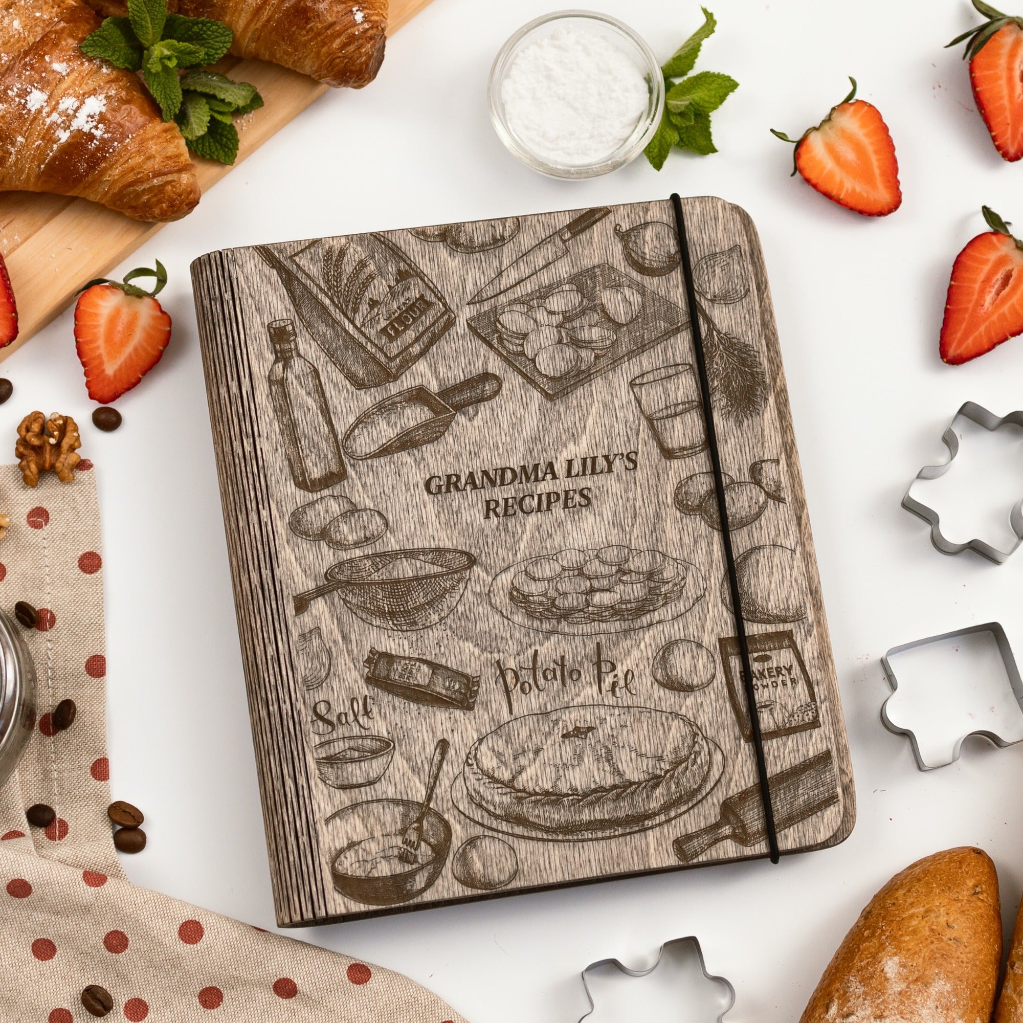 Notebook titled 'Grandma Lily's Recipes' surrounded by baking items on a white surface