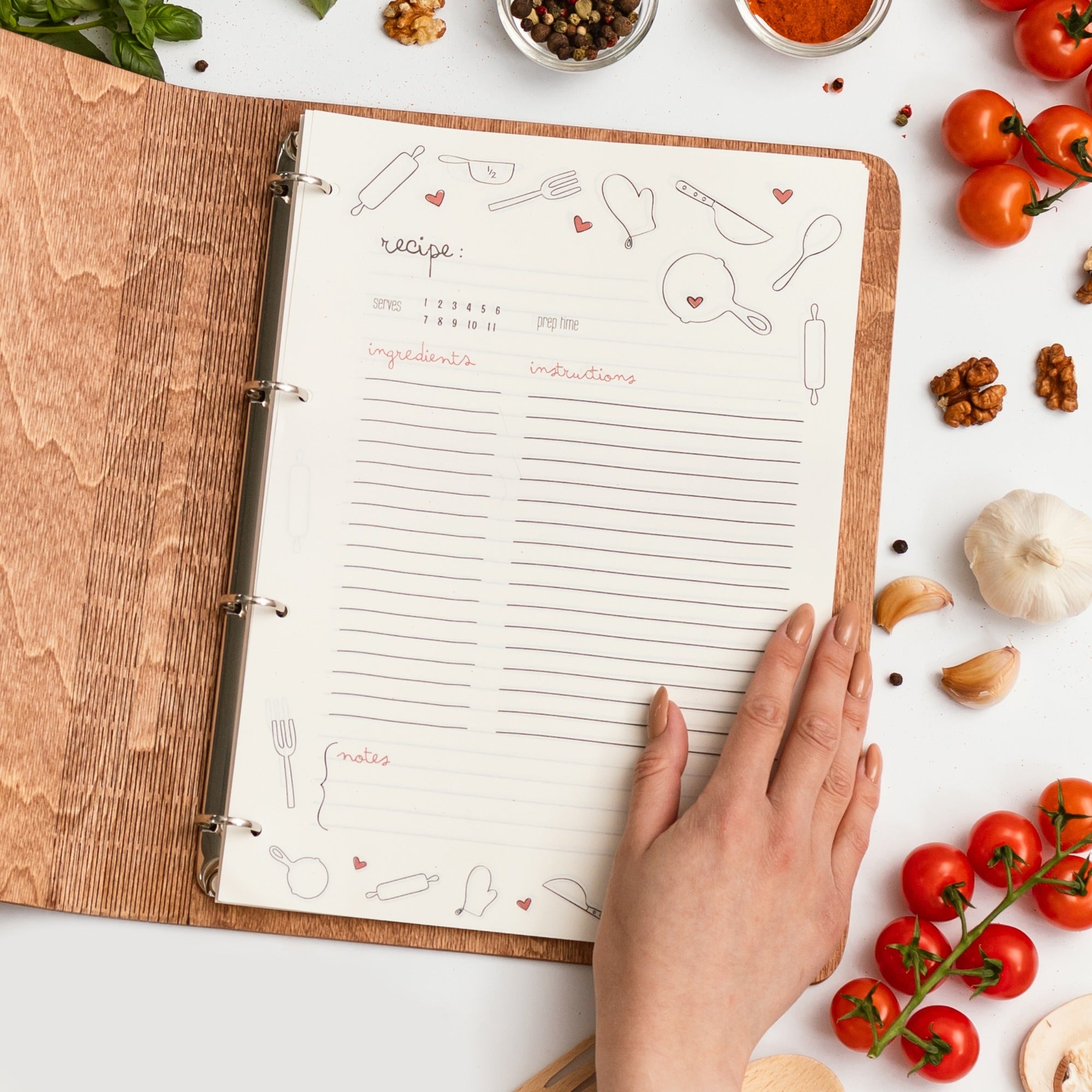 Open recipe book with hand on a table surrounded by ingredients
