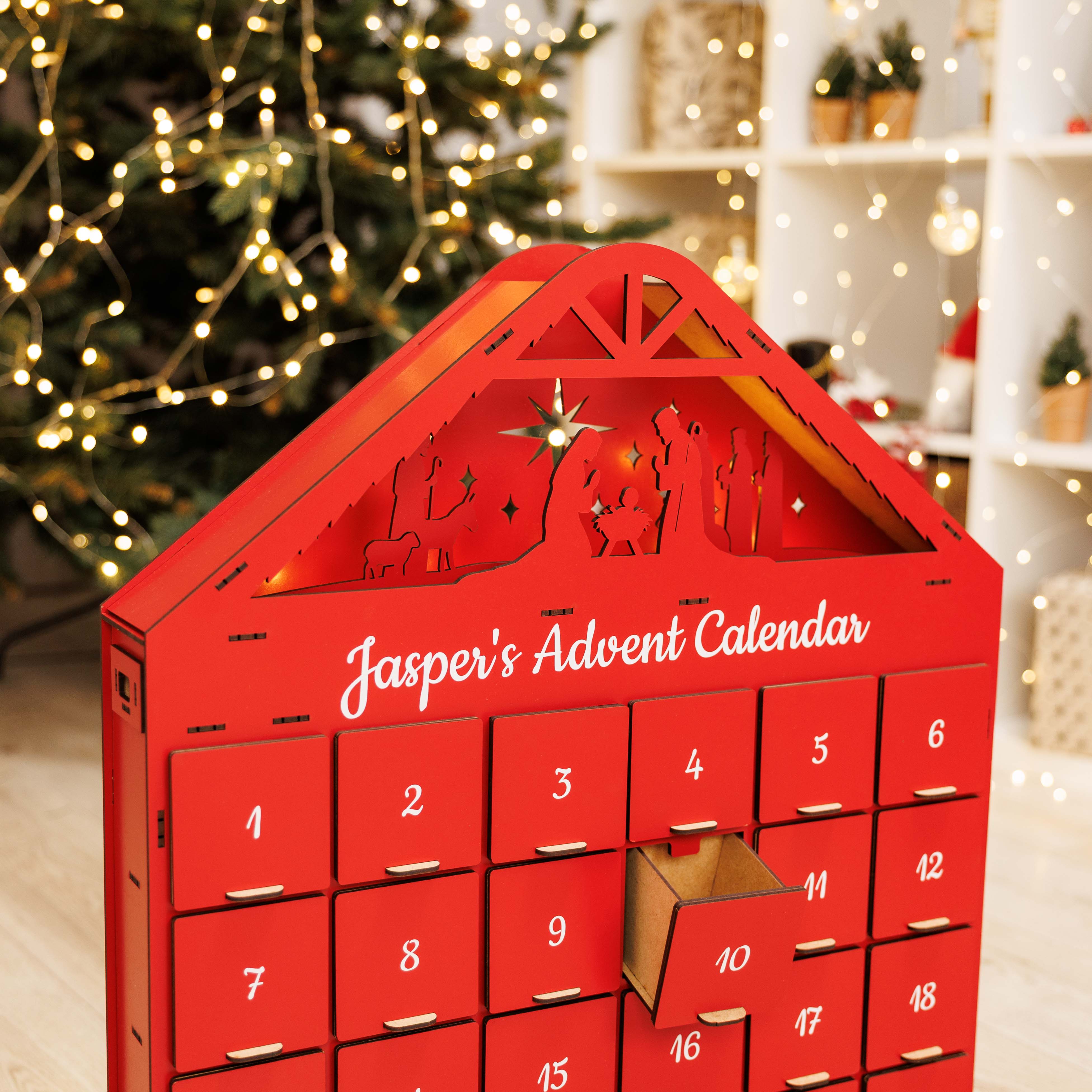 Red advent calendar with 'Jasper's Advent Calendar' text, Christmas tree and decorations in the background