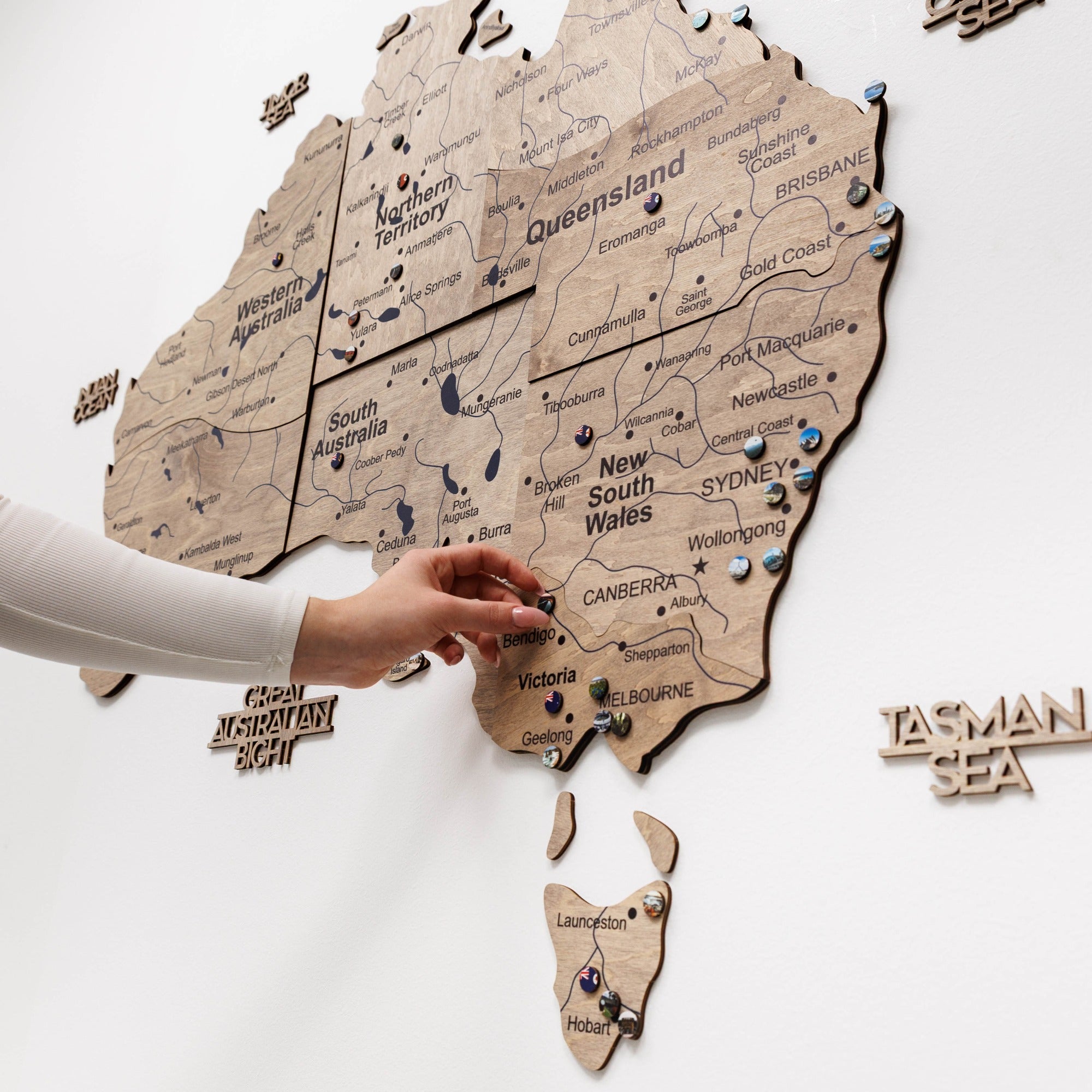 Wooden map of Australia with a hand pointing to Sydney