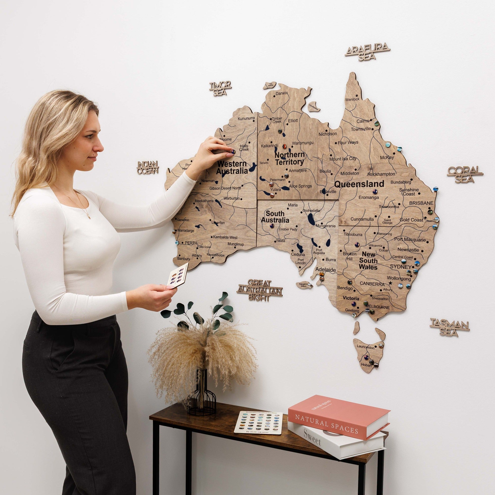 Woman interacting with a wooden map of Australia on a wall.