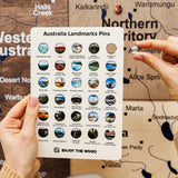 Card with Australia Landmarks Pins held by a hand against a map background