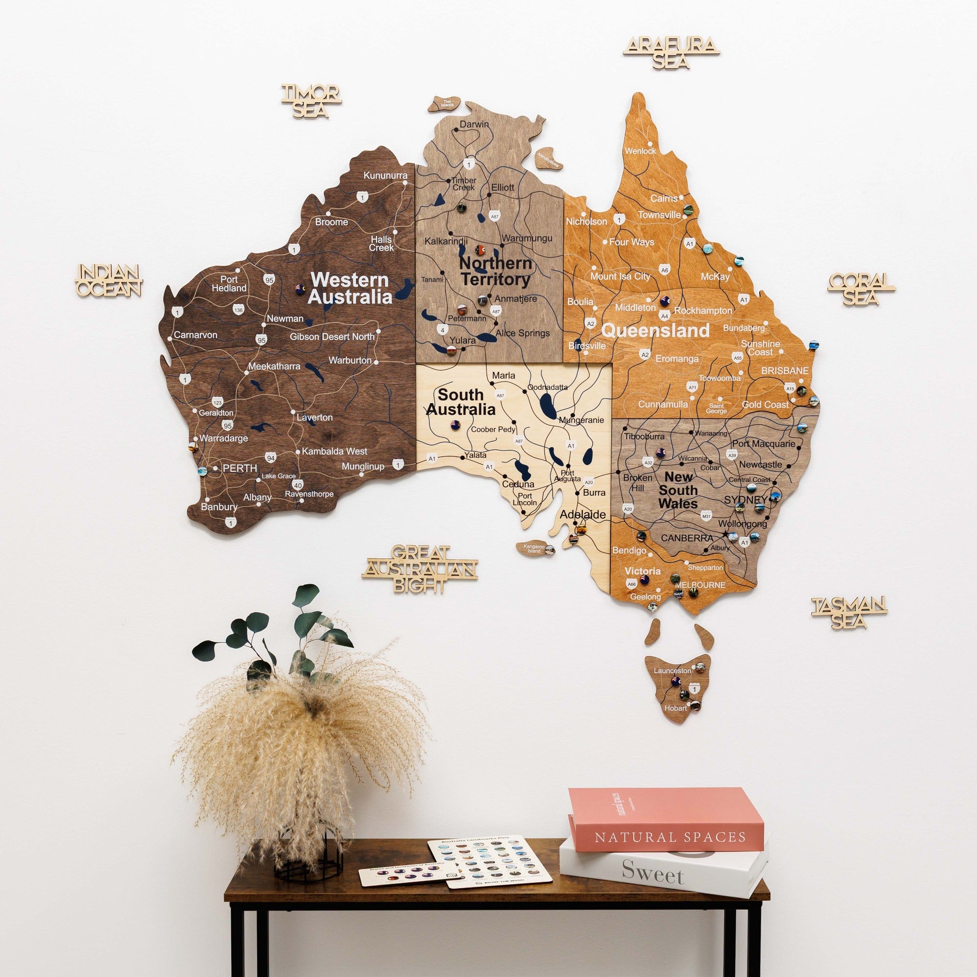 Wall-mounted map of Australia with wooden texture on a white wall above a wooden table.
