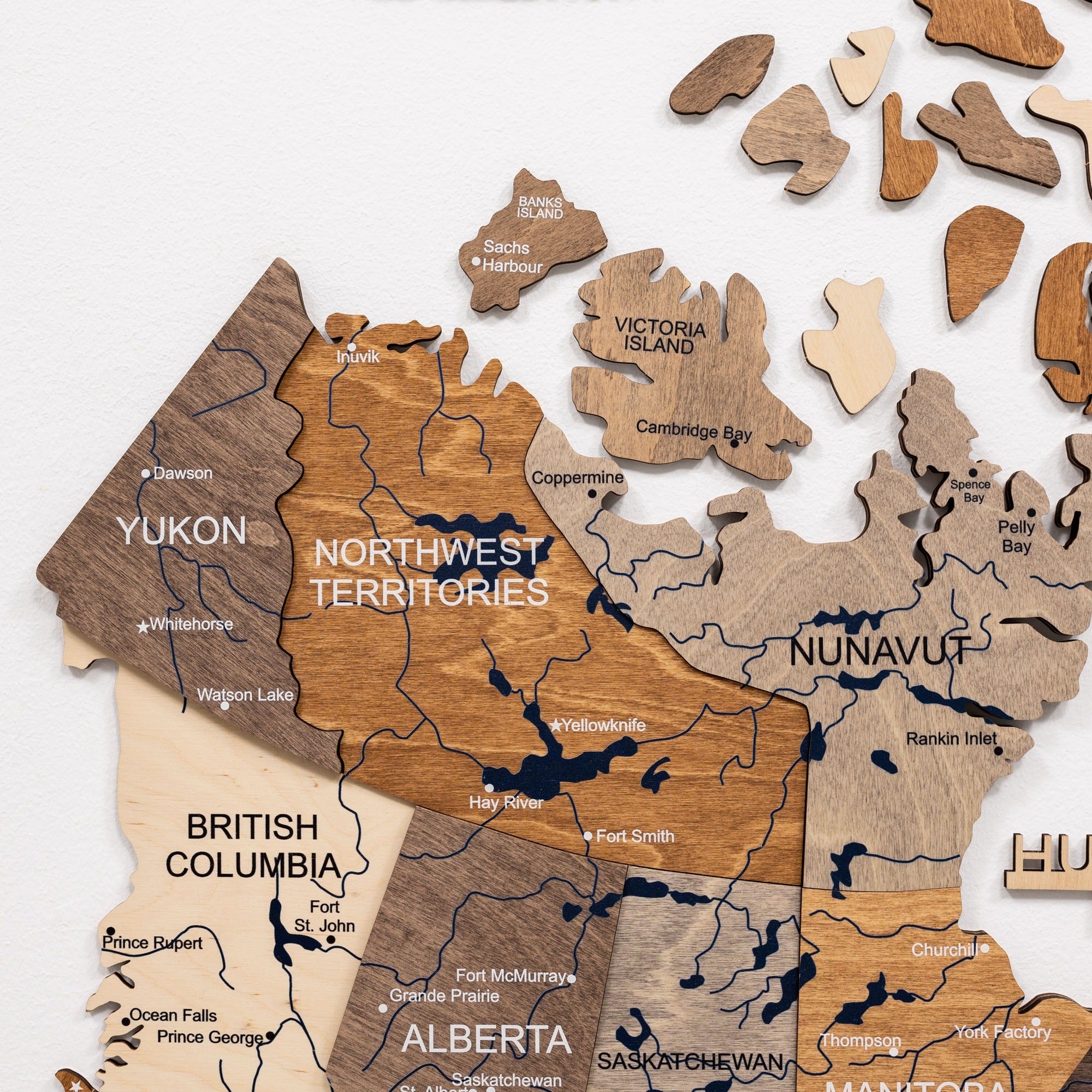 Wooden map of Canada with provinces and territories in different colors on a white background