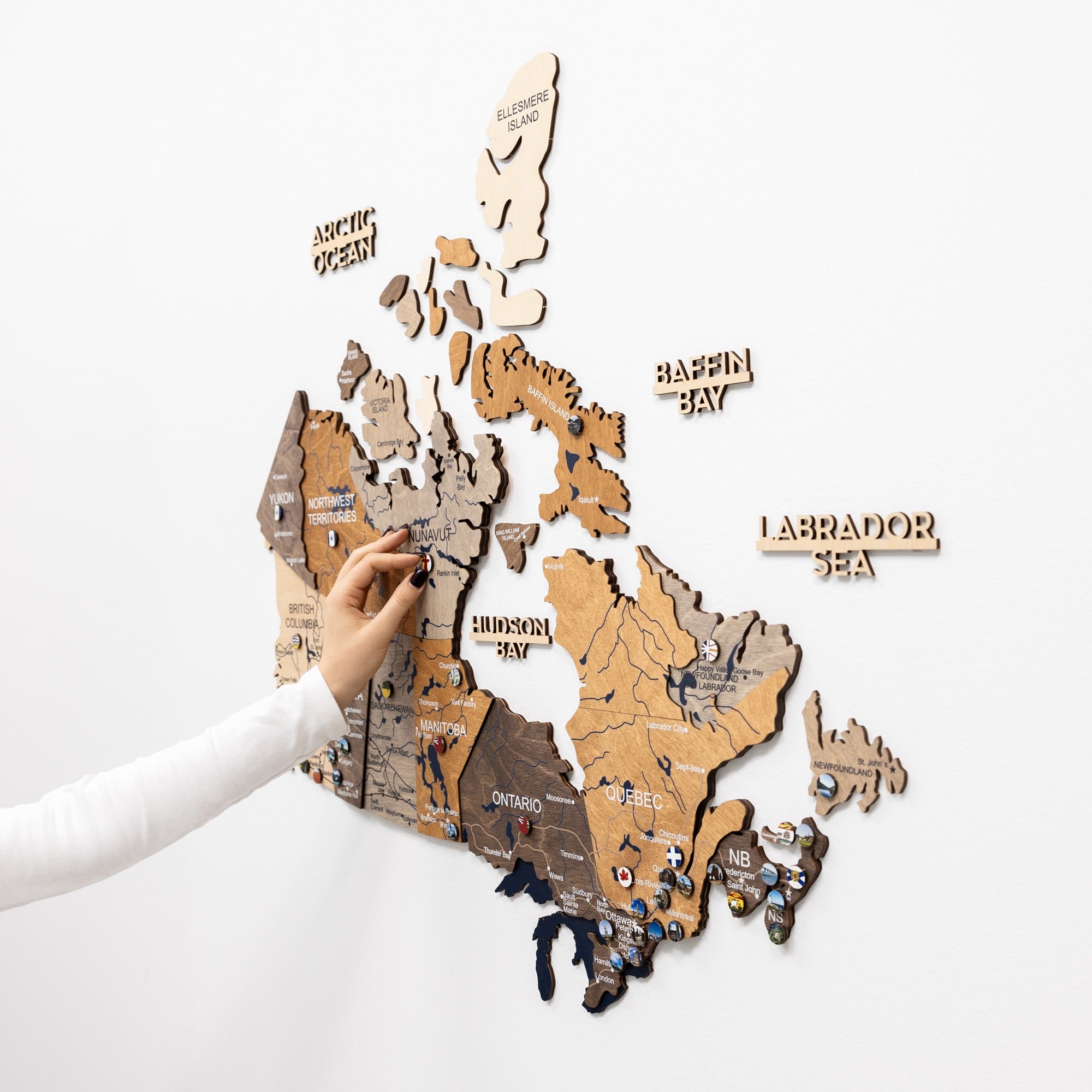 Wooden map of Canada with pins on a white background