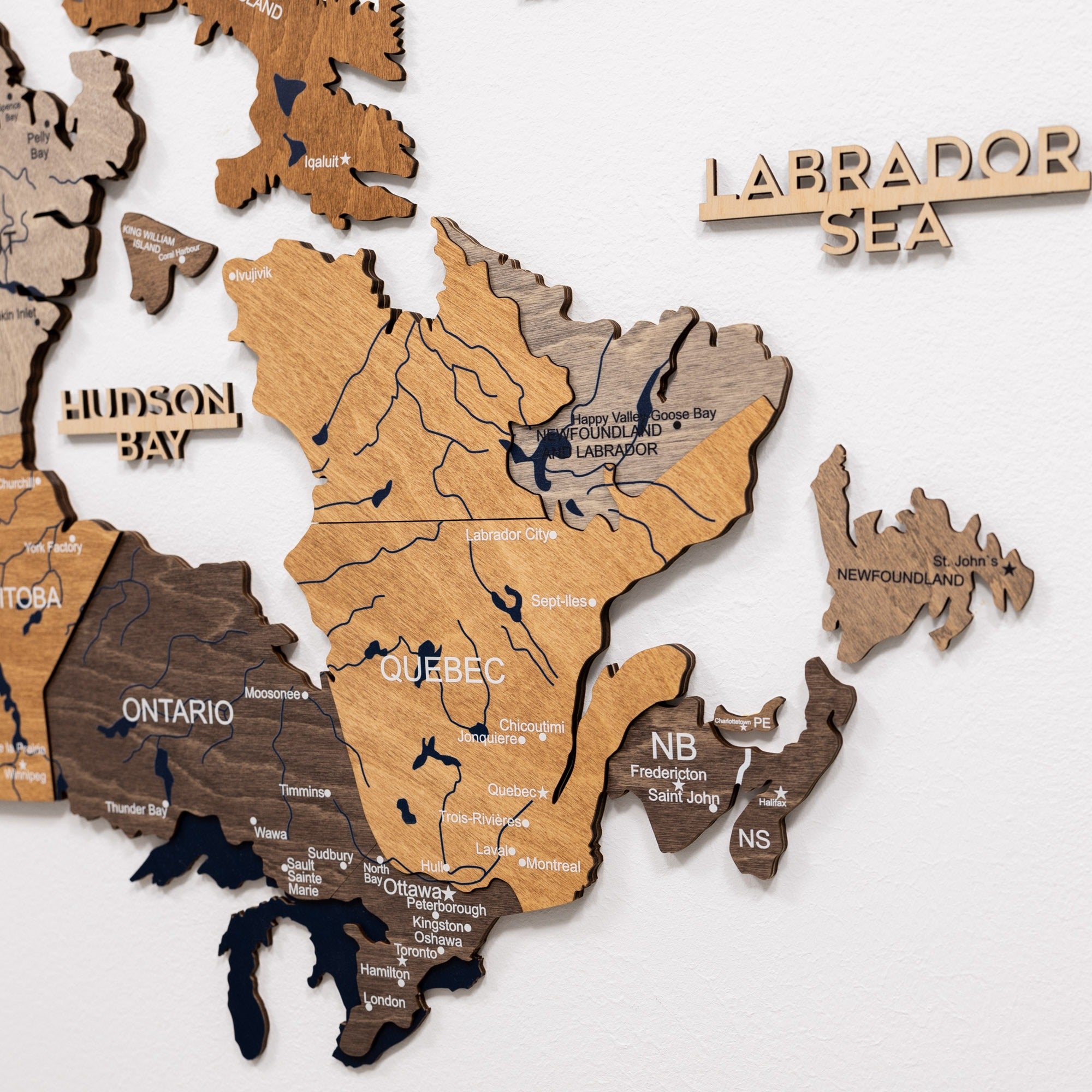 Wooden map of Canada with labeled provinces on a white background