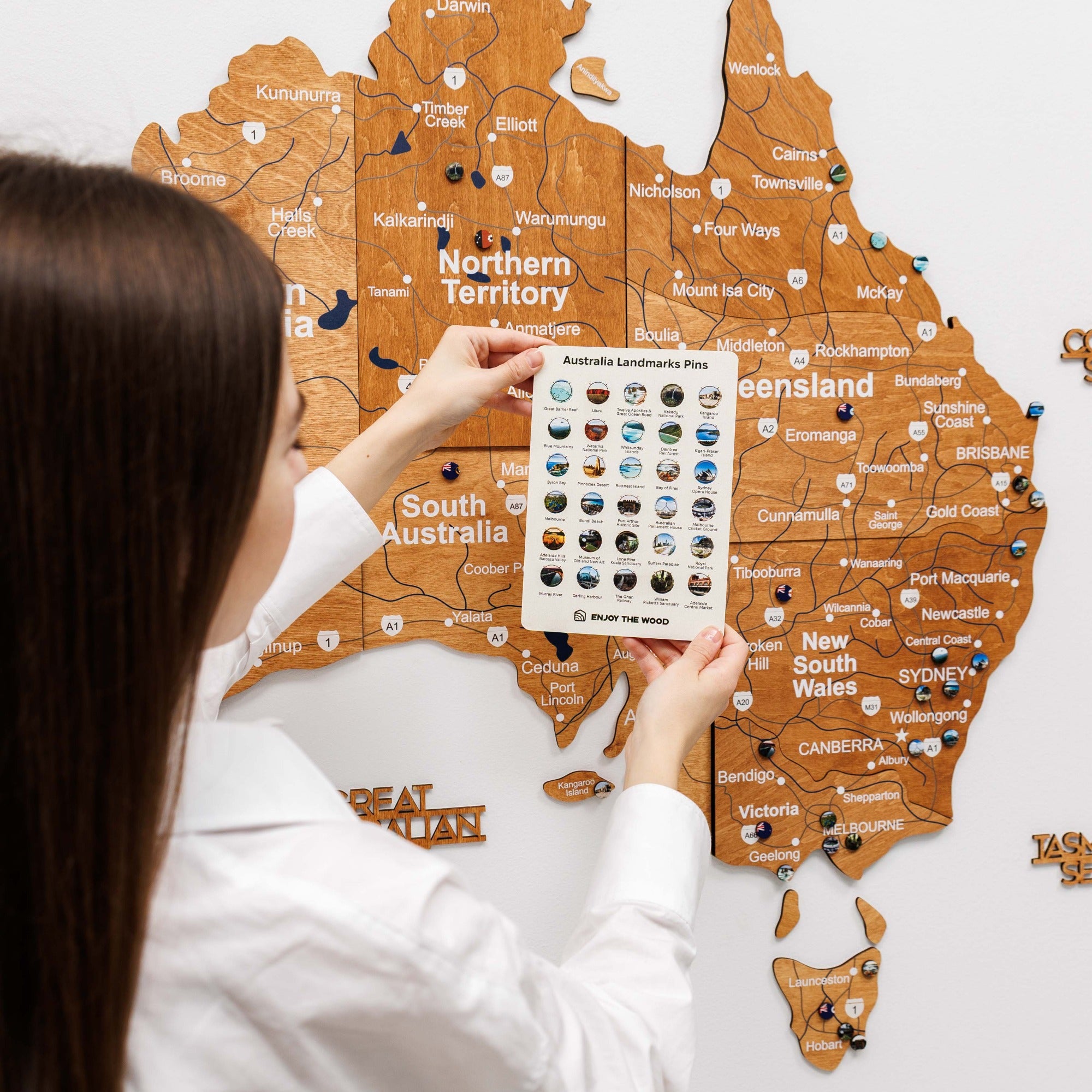 Person holding a map of Australia with a magnifying glass over New South Wales.