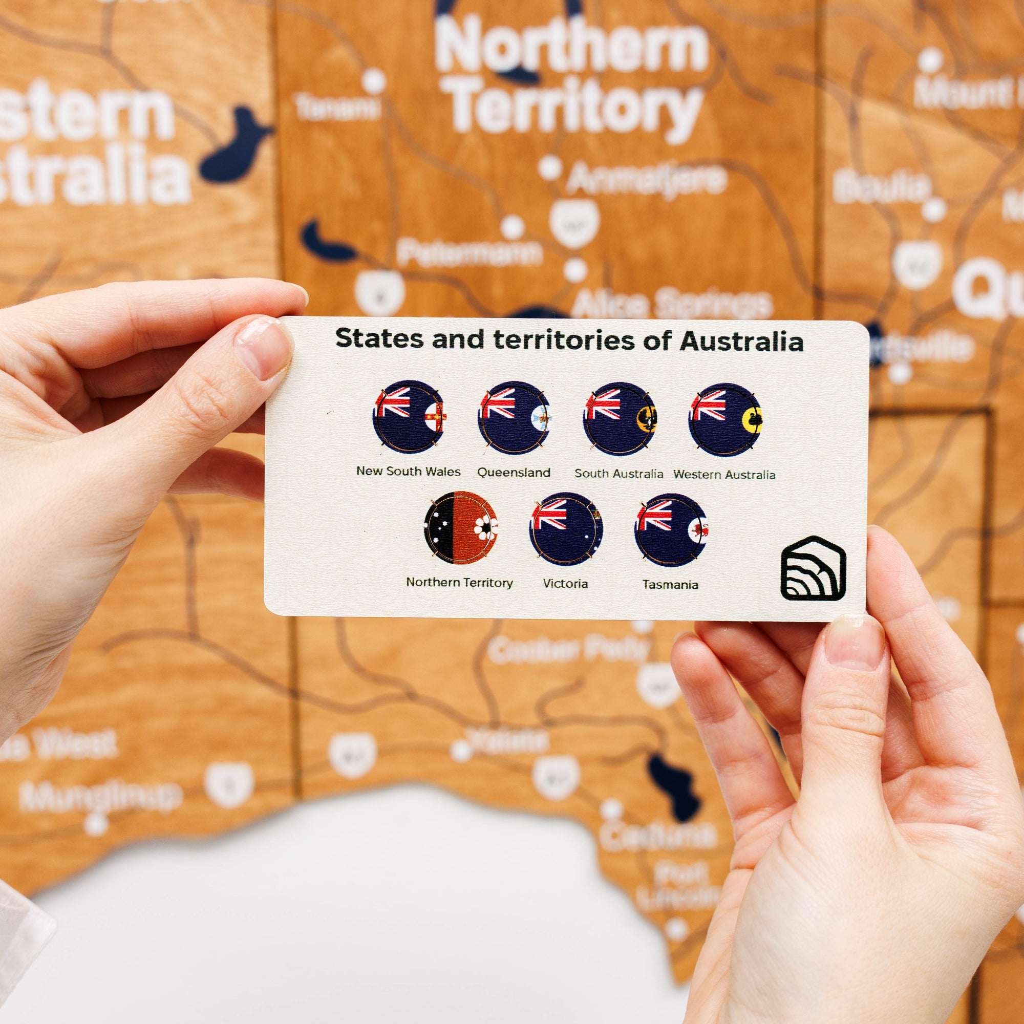 Card with flags of Australia's states and territories held over a map of Australia.