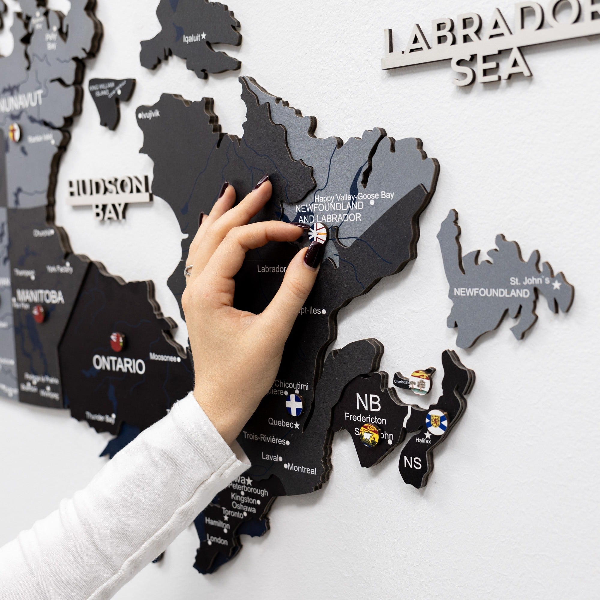 Hand interacting with a black map of Canada on a white background