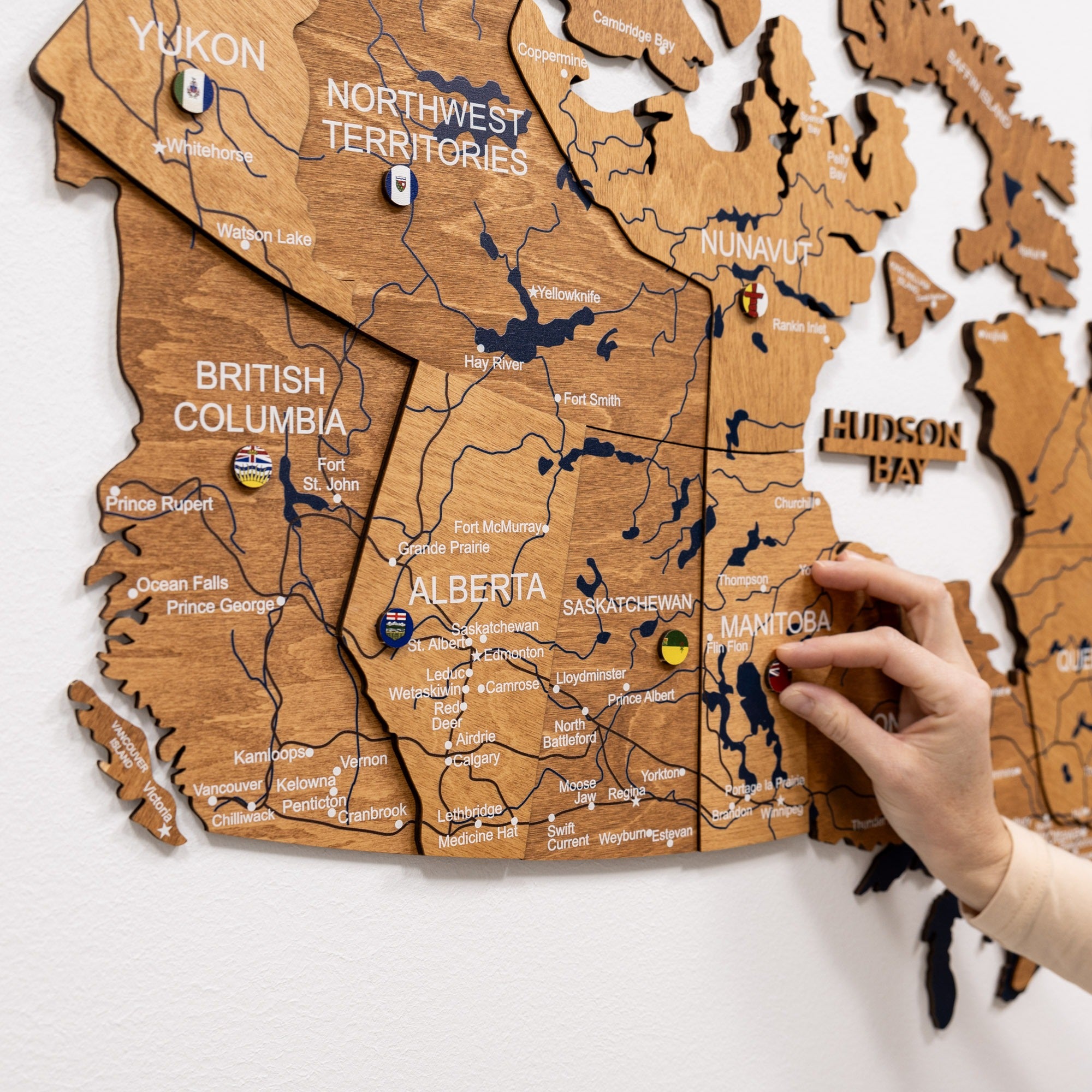 Wooden map of Canada with a hand interacting with it