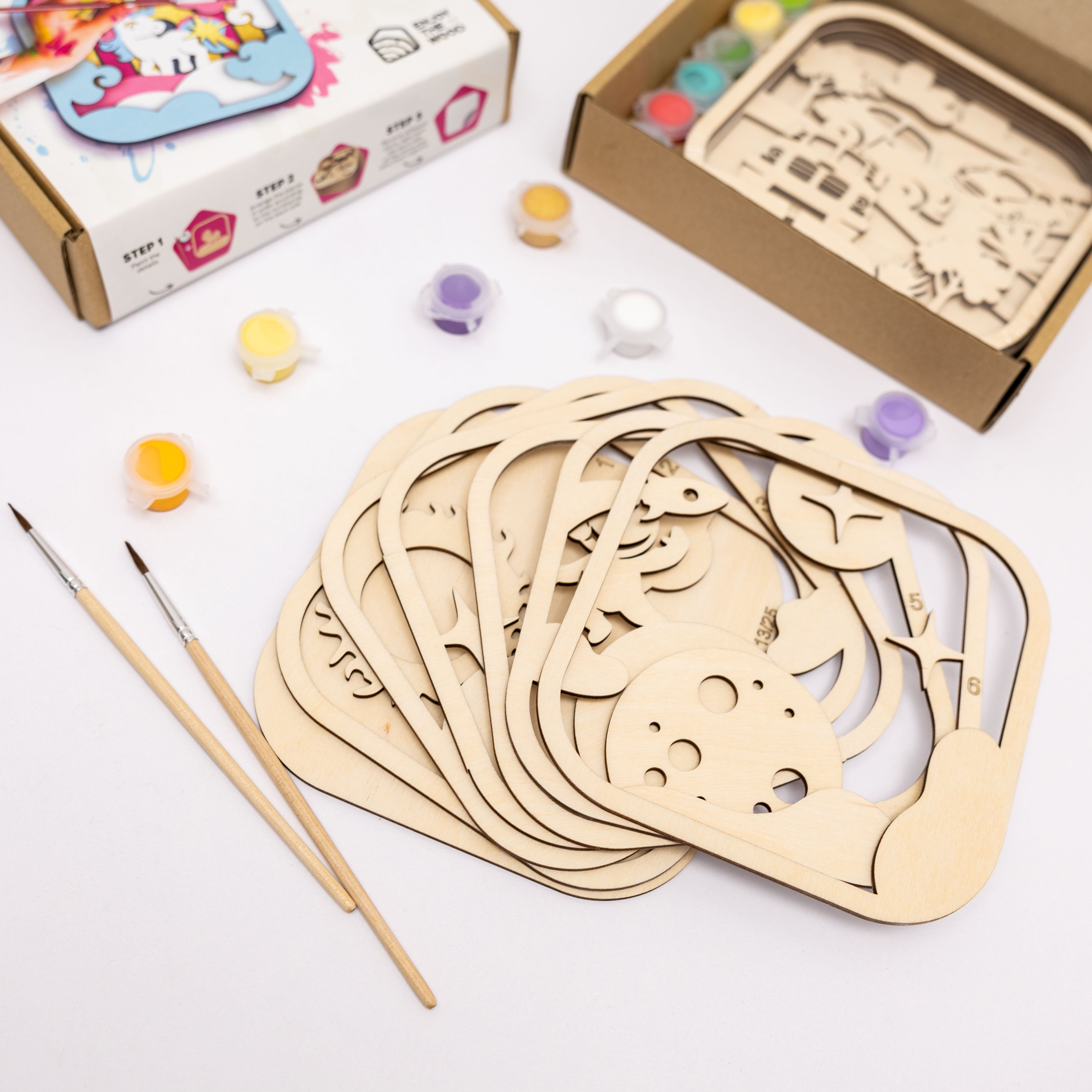 Wooden craft pieces with paint and brushes on a white background