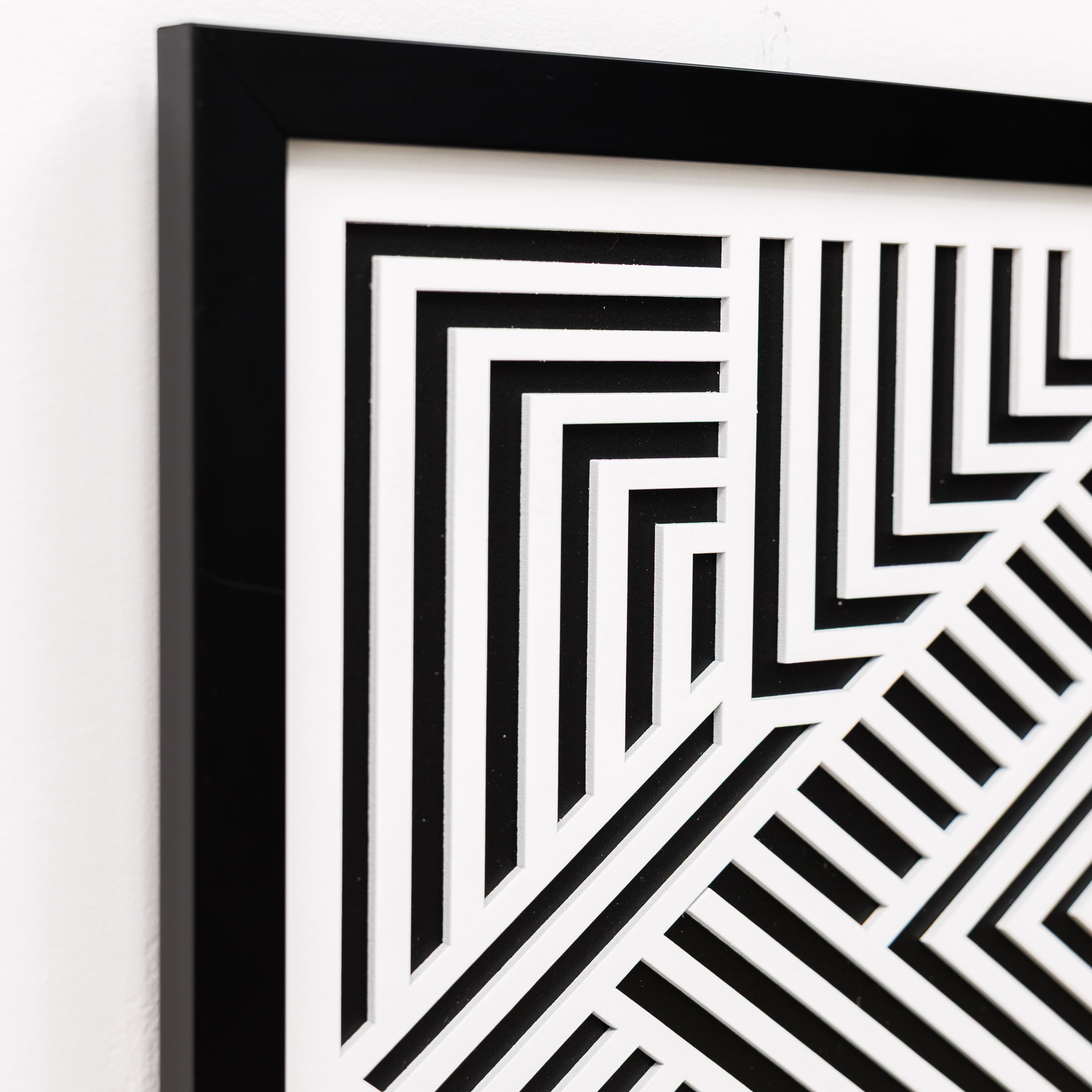 Framed black and white geometric pattern on a white wall