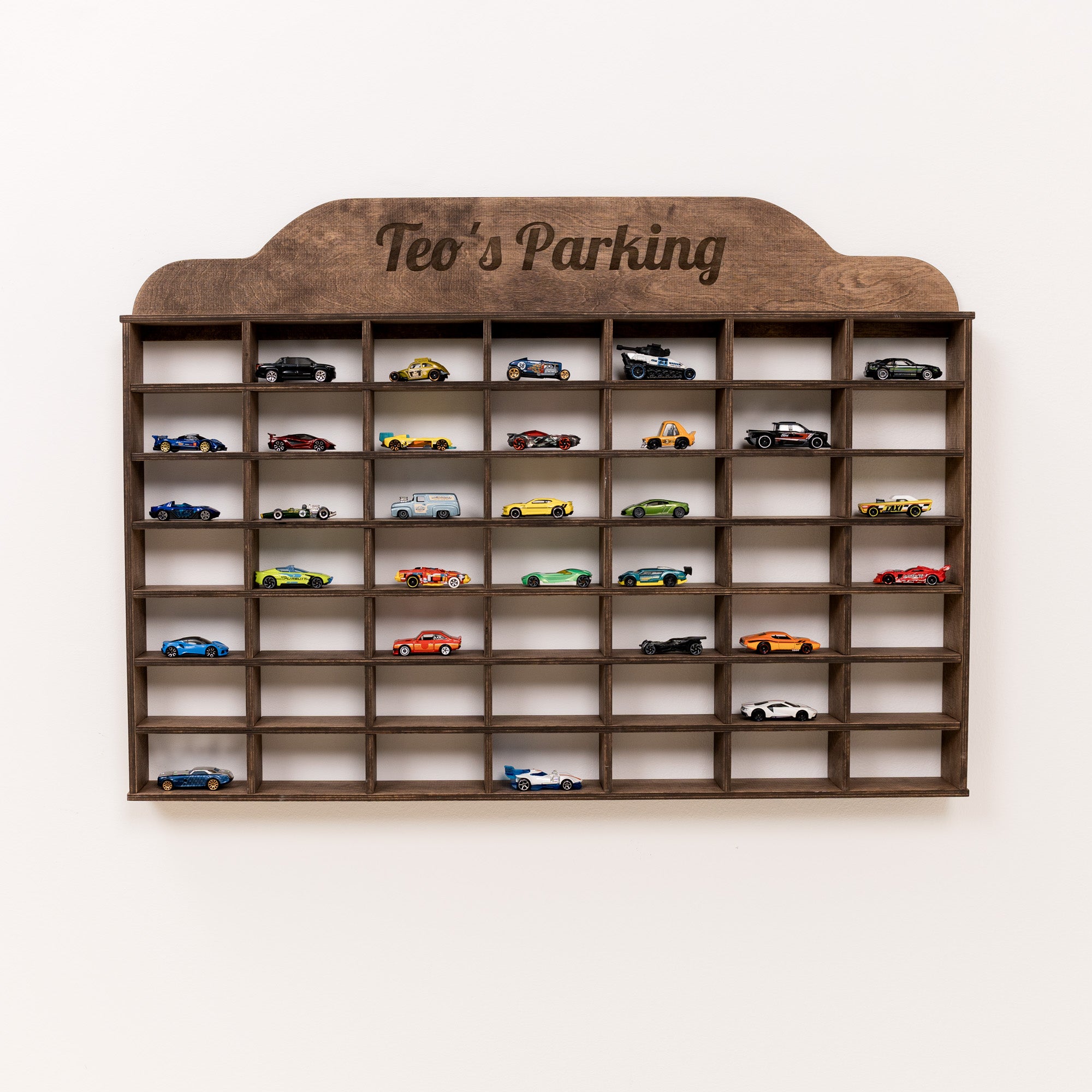 Wooden wall shelf with 'Teo's Parking' sign, displaying various model cars.