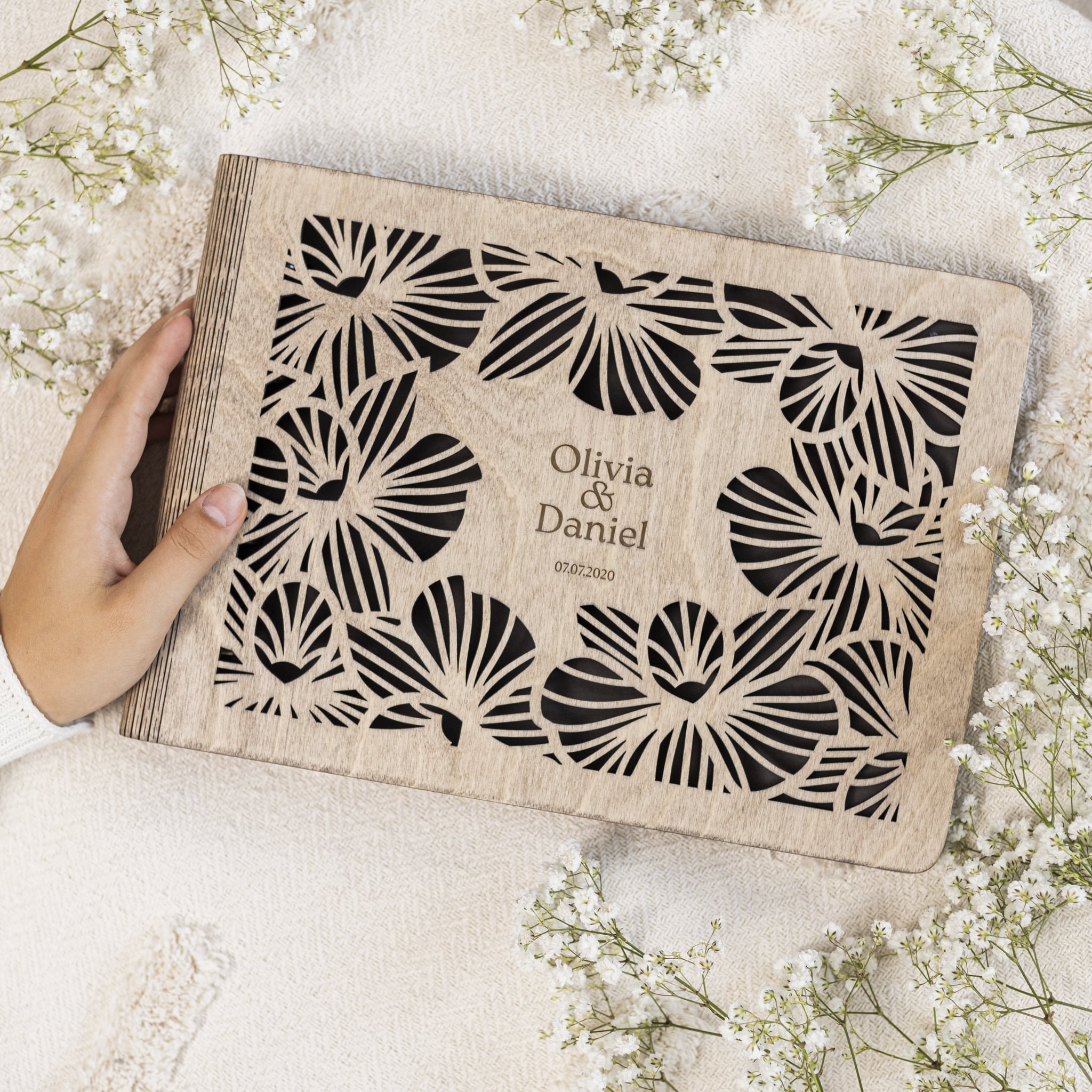 Personalized wooden nameplate with butterfly design held by a hand on a light background with flowers.