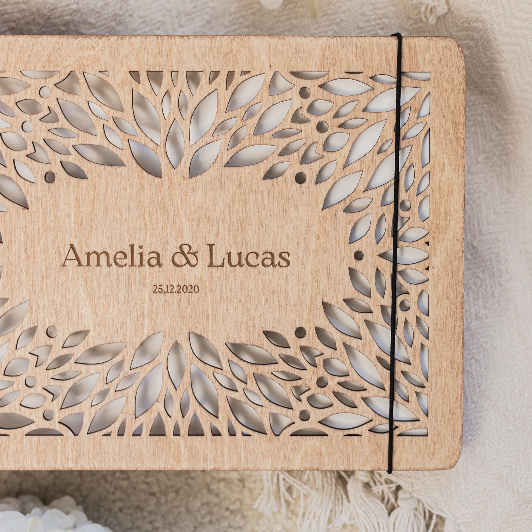 Wooden box with laser-cut design and engraved text 'Amelia & Lucas' on a neutral background