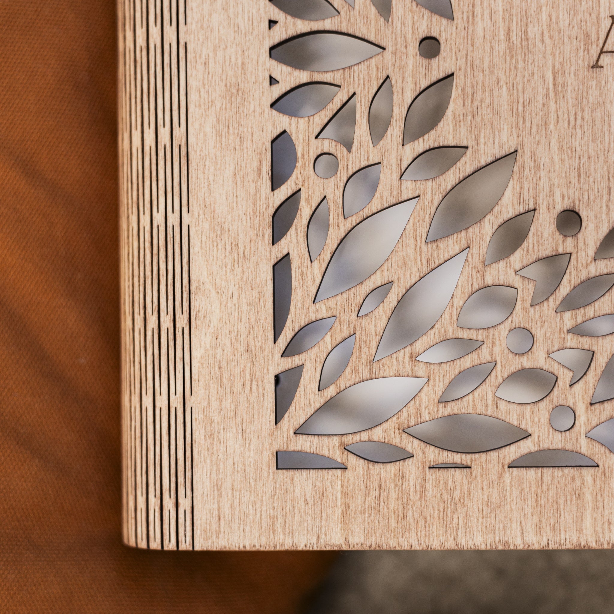 Wooden panel with laser-cut leaf pattern on a wooden surface