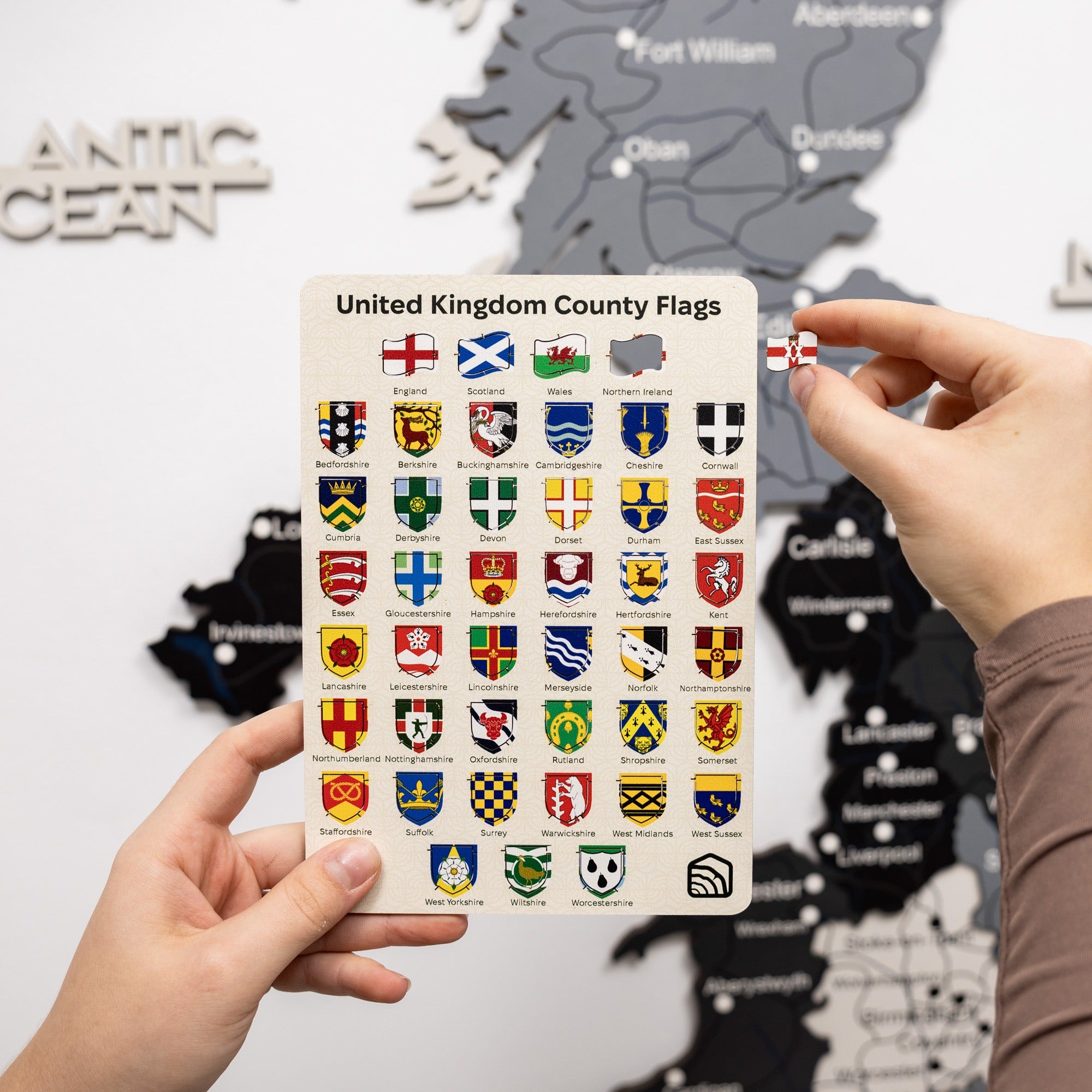 Card with United Kingdom county flags held by a person against a map background