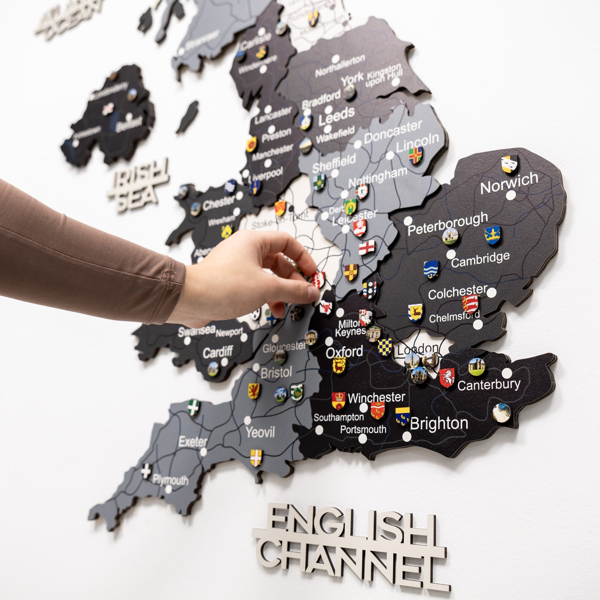 Map of England with cities labeled, pinned by a hand on a white background