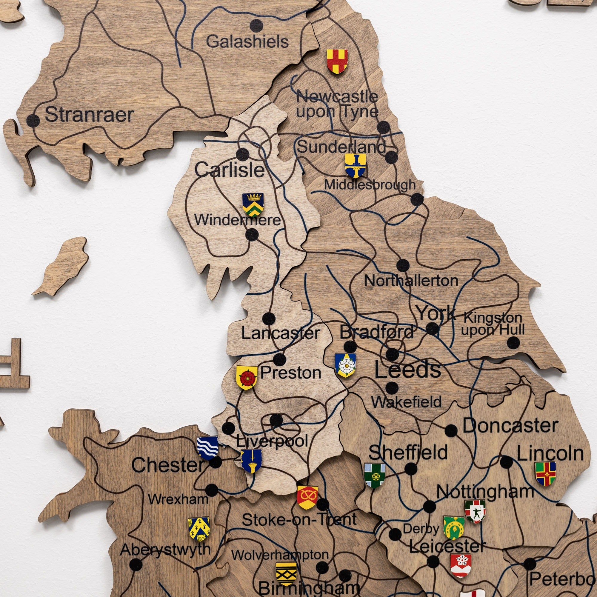 Wooden map of the United Kingdom with city names and small flags on a white background