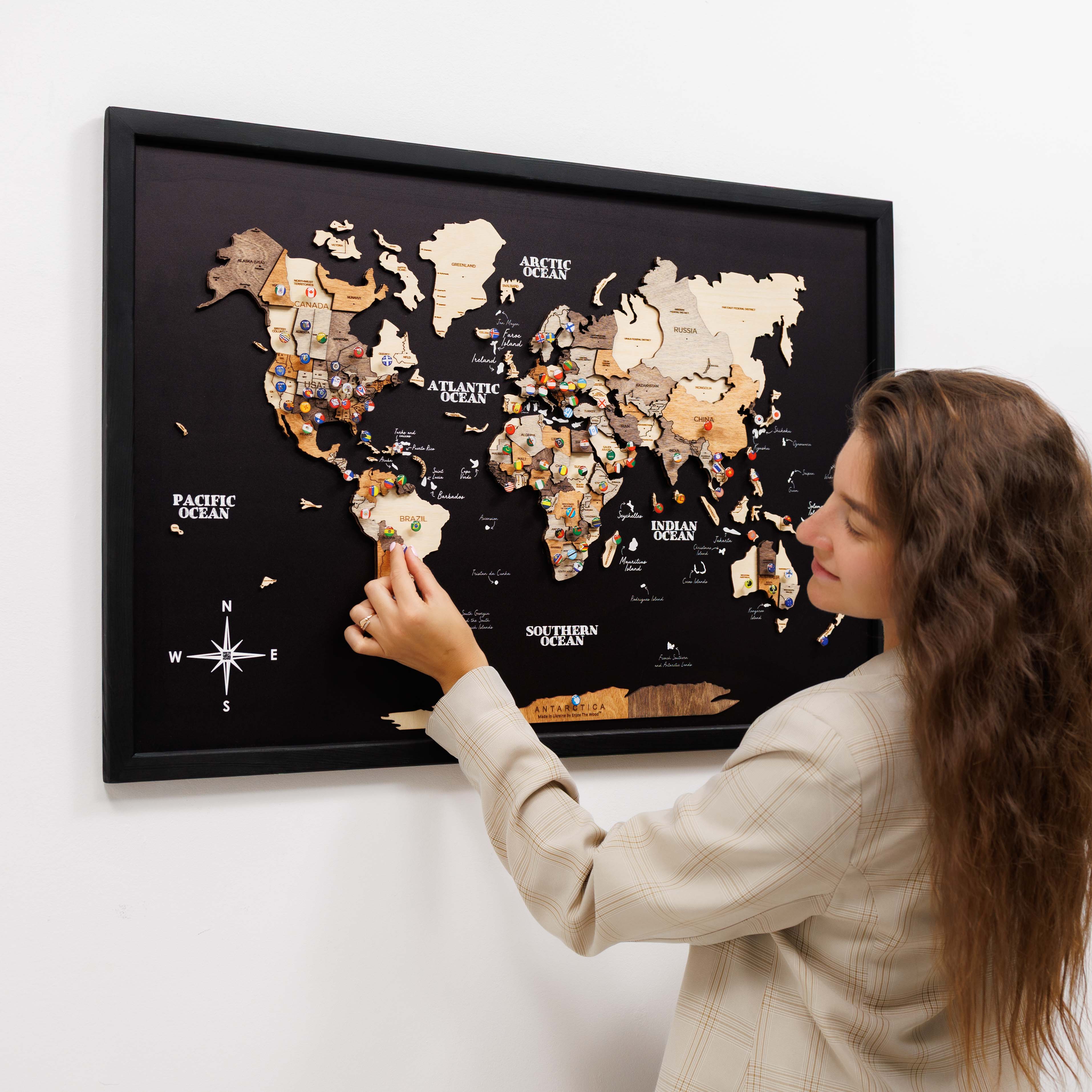 Woman interacting with a world map poster on a wall