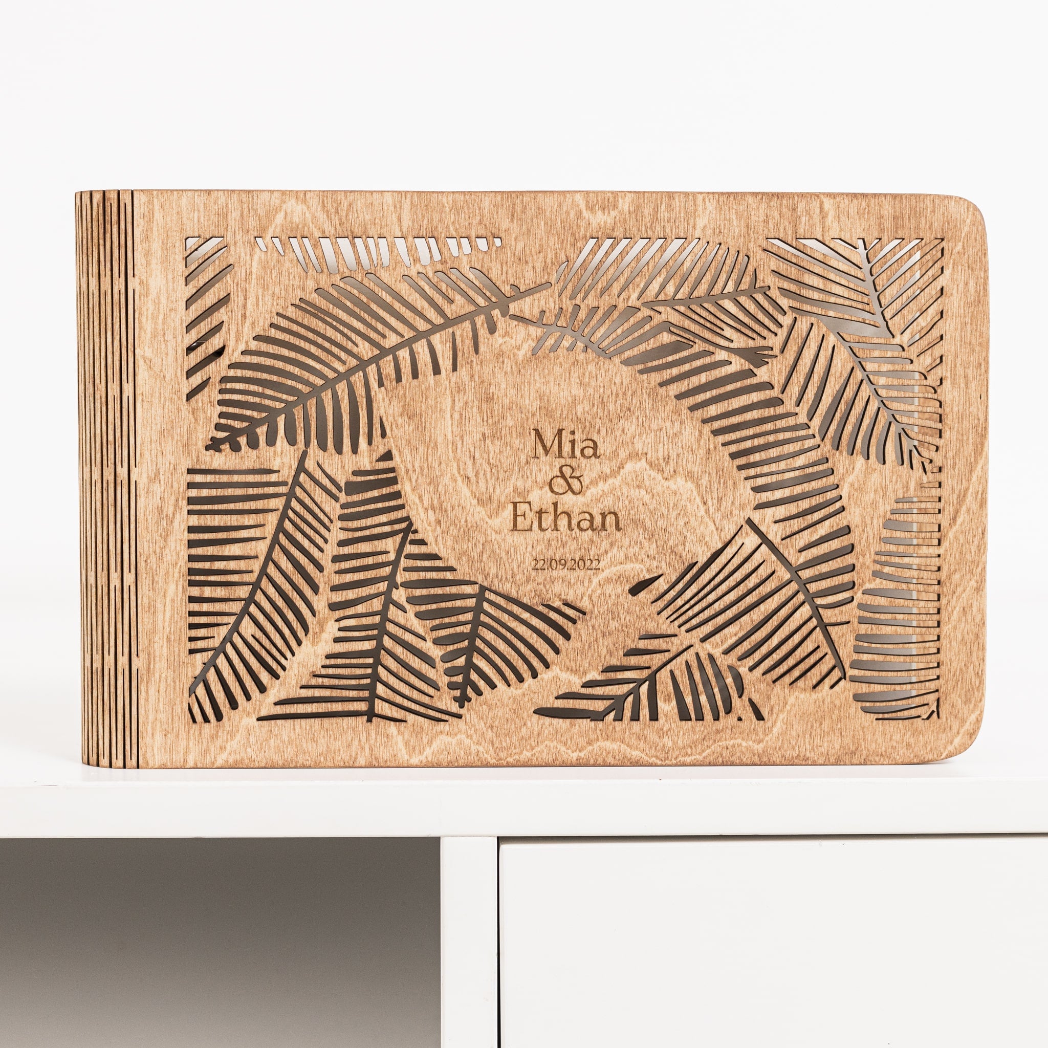 Wooden book with engraved leaf design and text on a white background