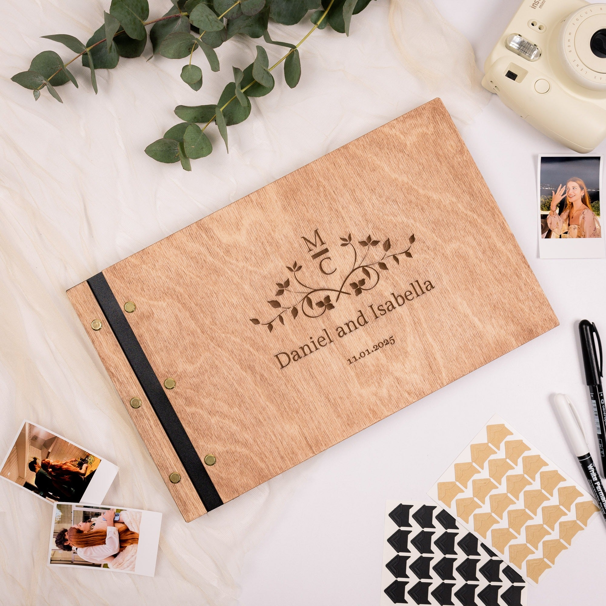 Personalized wooden photo album with engraved text on a light surface with decorative elements.