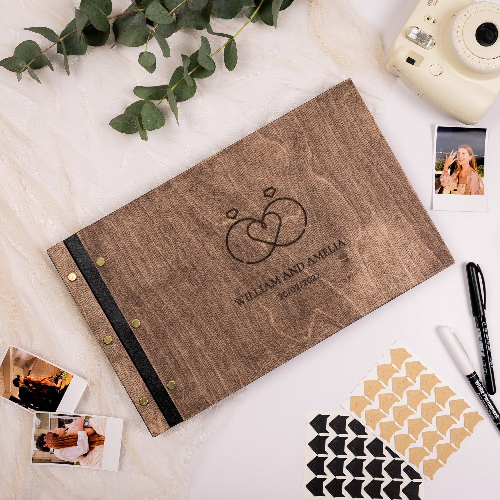 Wooden photo album with engraved text on a white surface with decorative elements.