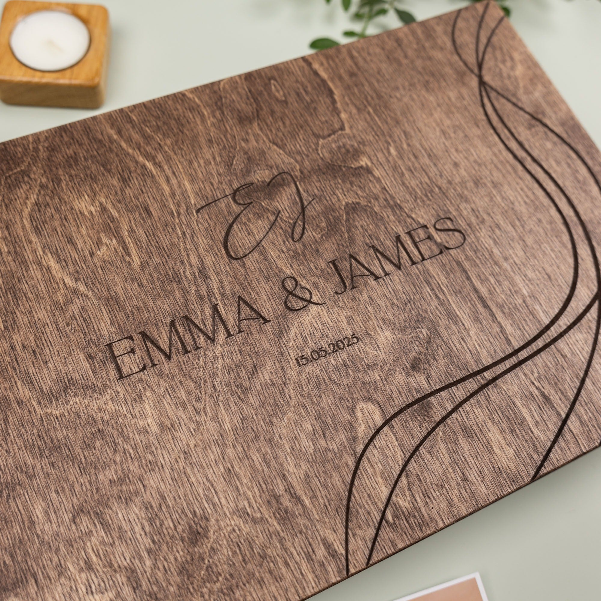 Wooden album with engraved names 'Emma & James' and date, on a light background.